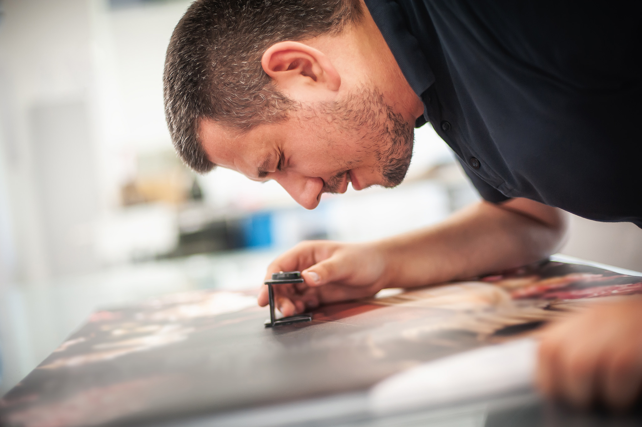 Man carefully inspecting printed material with a magnifying loupe
