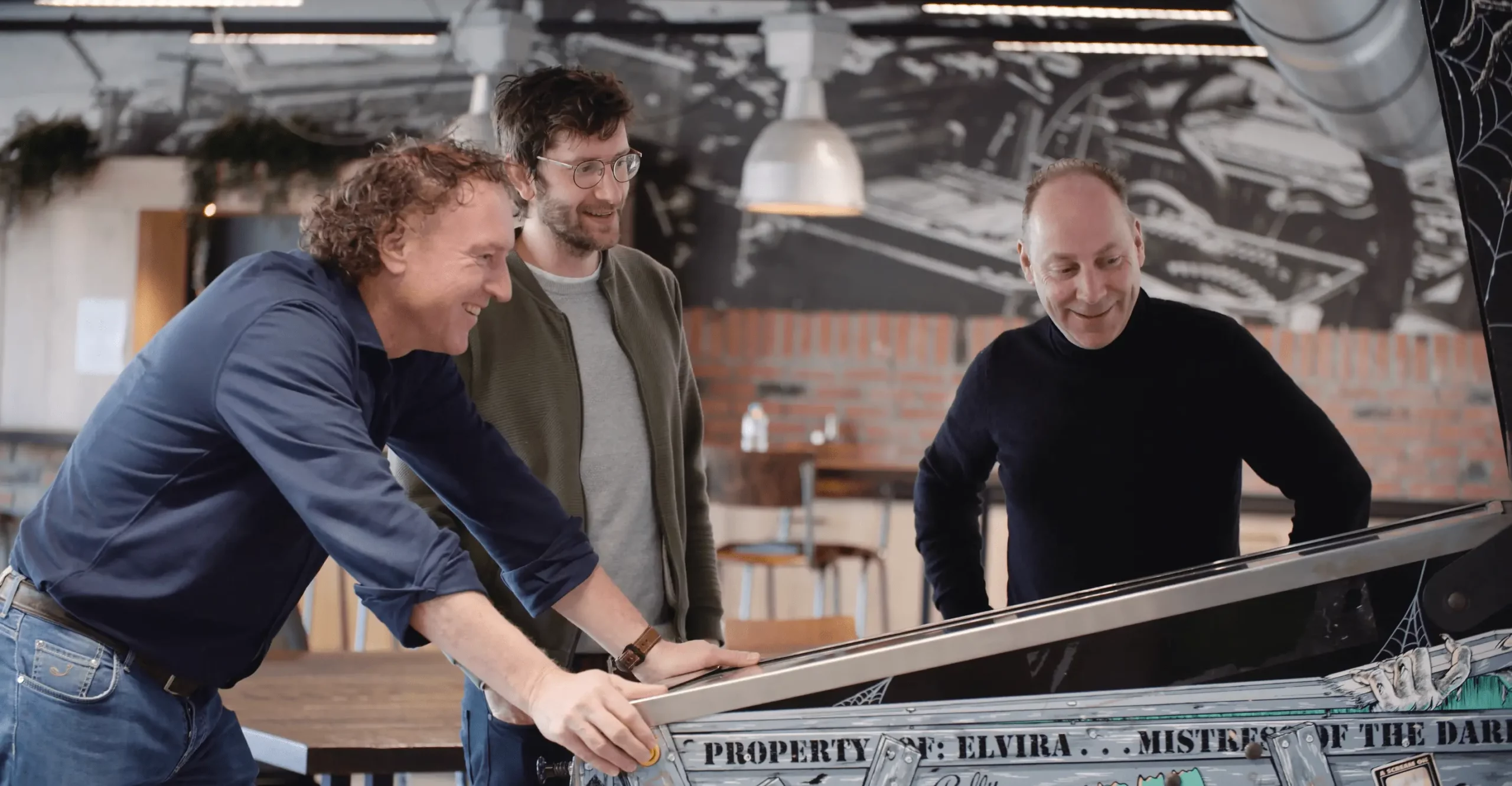 3 Men Standing at Pinball Table