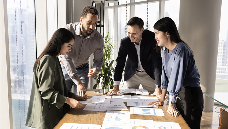 Team in office surrounding a table with paperwork