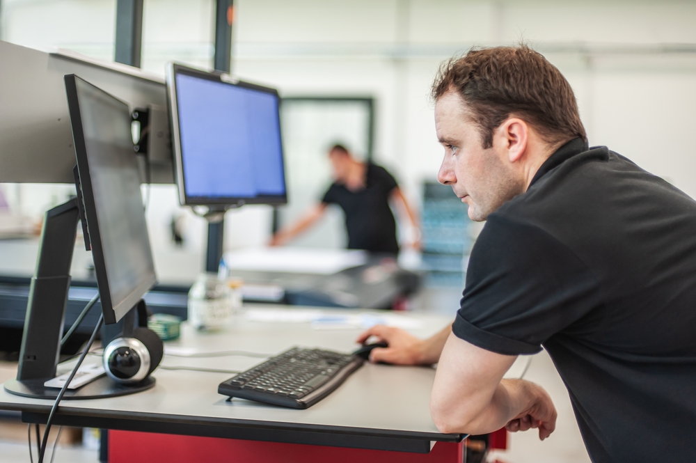 Print operator reviewing data on their computer in a print warehouse