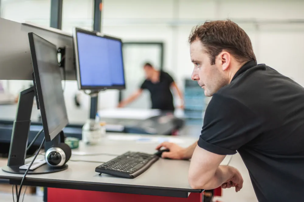 Print operator reviewing data on their computer in a print warehouse